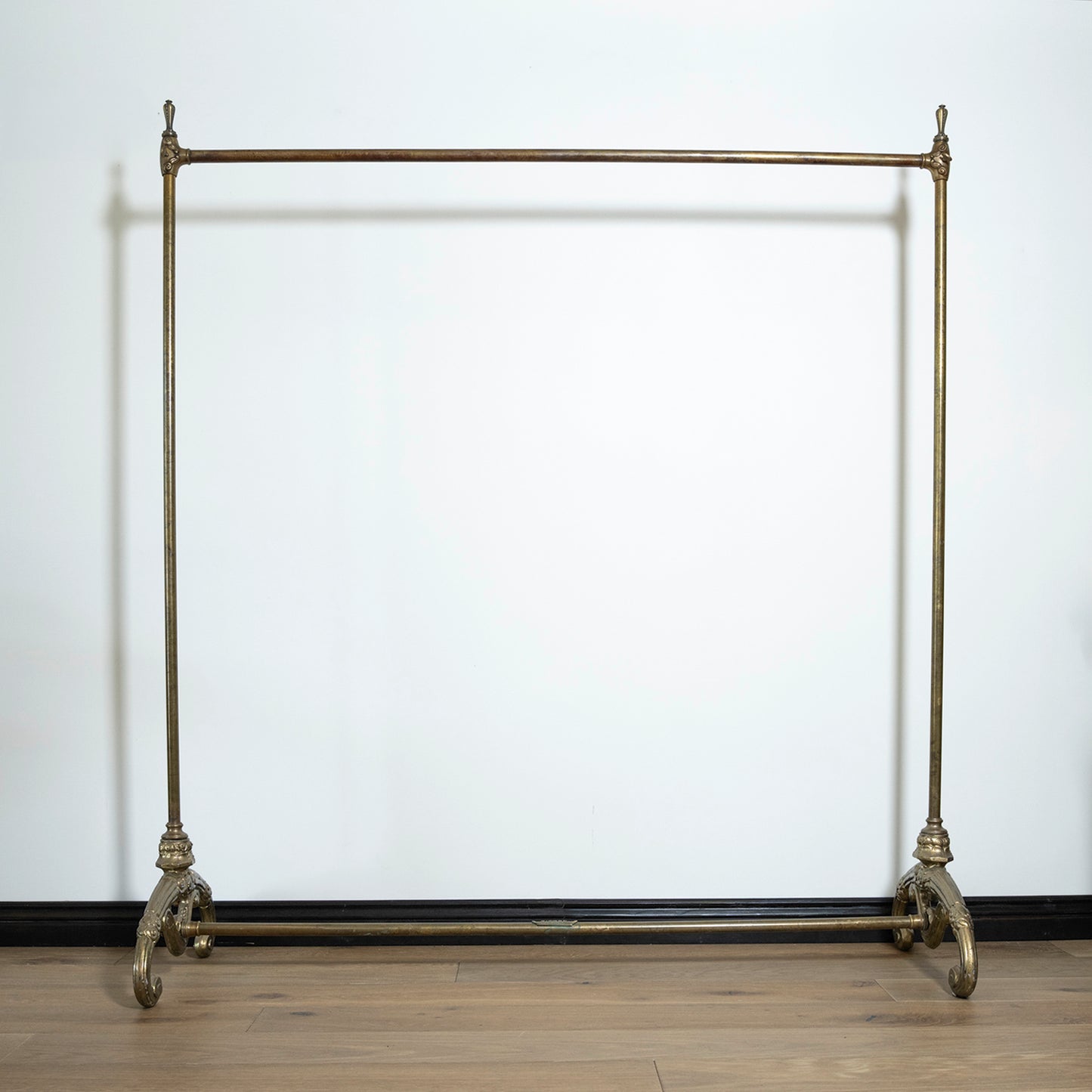 Vintage-style metal garment rack against a white wall.