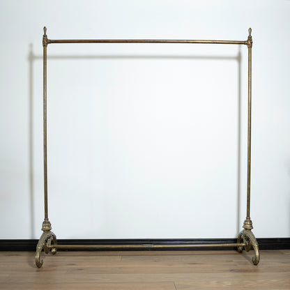 Vintage-style metal garment rack against a white wall.