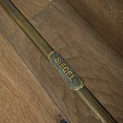Brass rack with 'SIEGEL' engraving on a wooden door