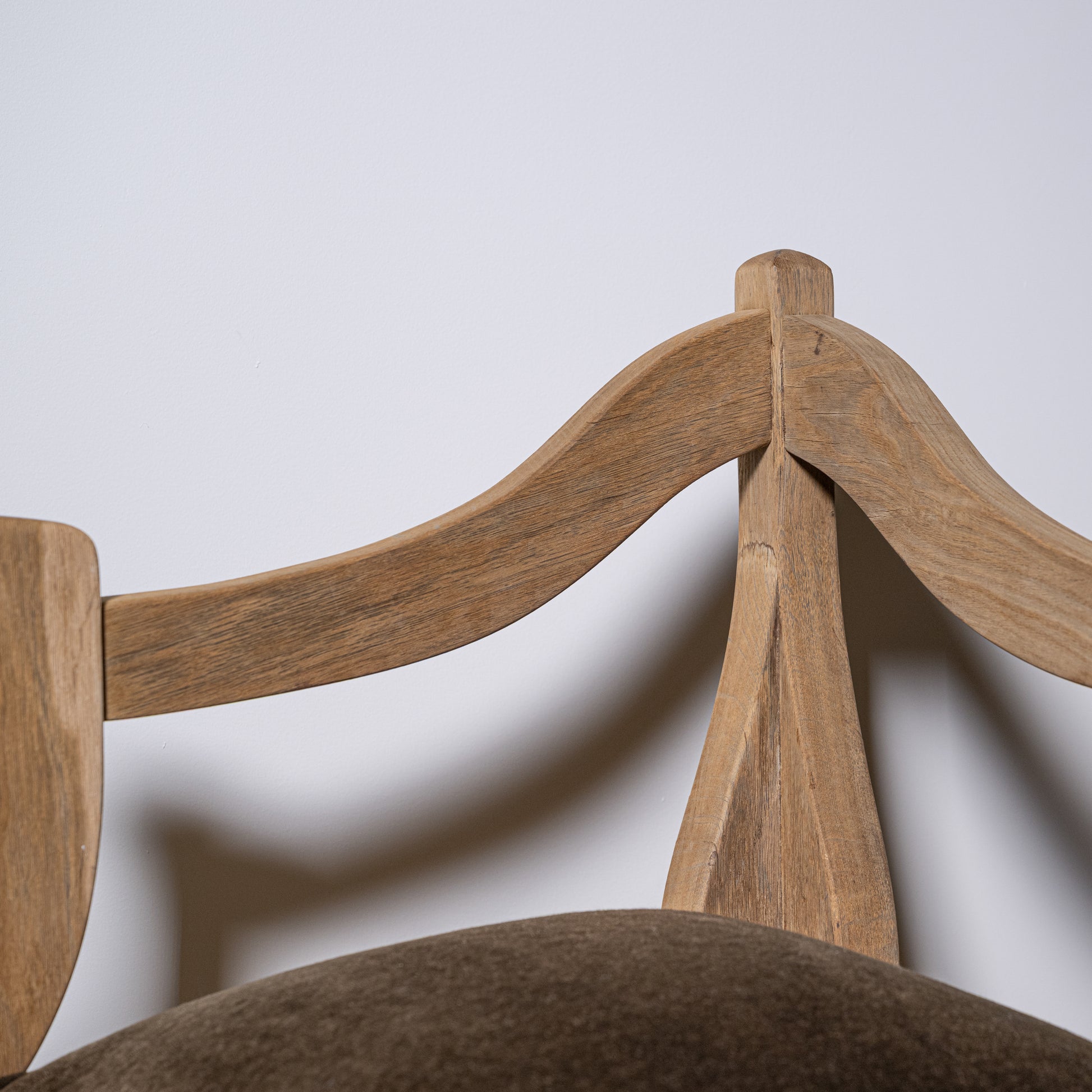 Light brown carved wood corner stool backrest with curved arms and central support post shown from the back side