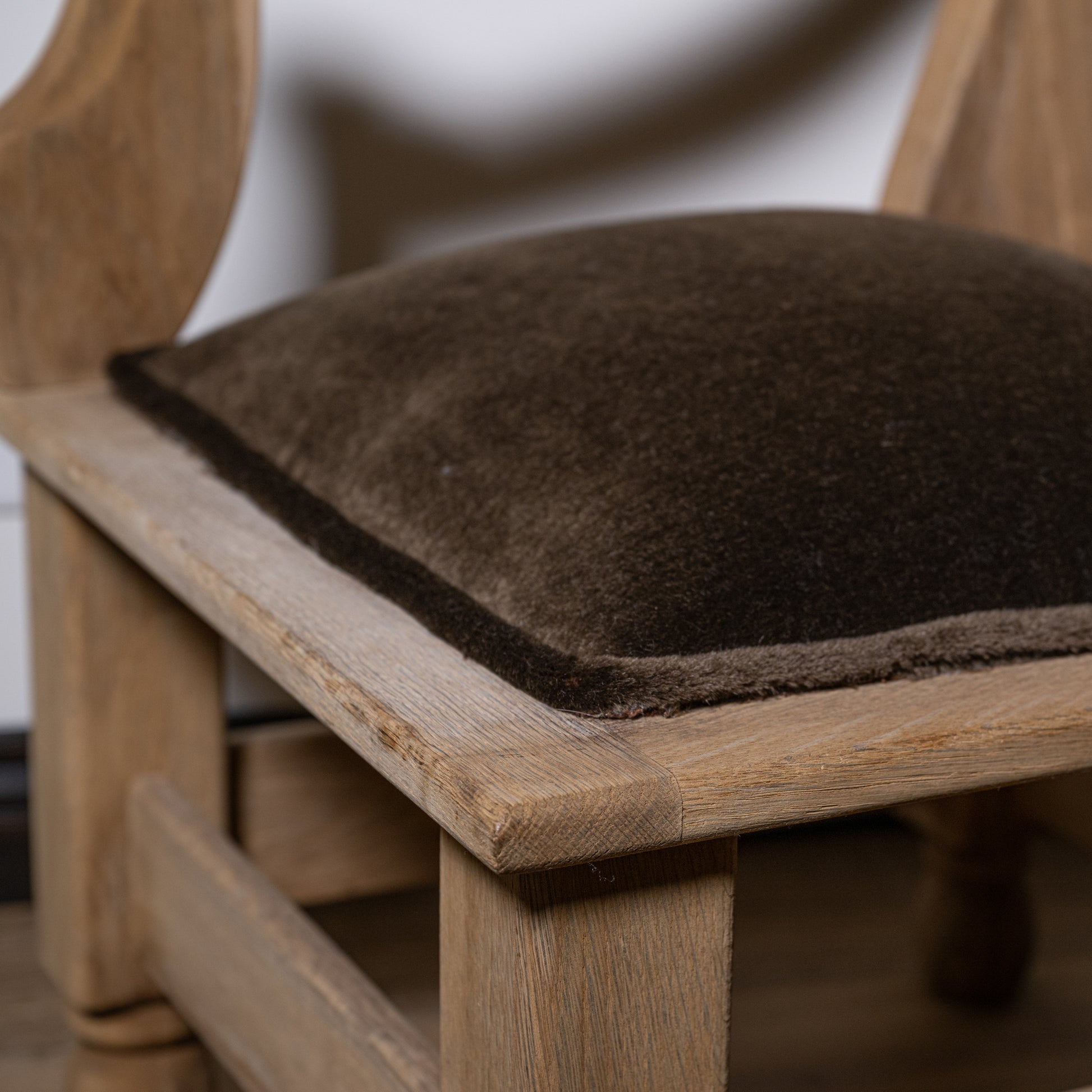 Brown sheepskin cushion on light oak carved wood corner stool with mohair seat showing front view
