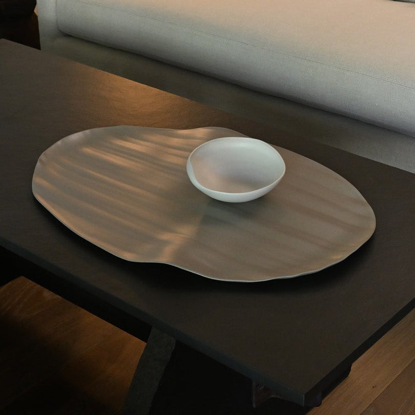 A sleek light brown leaf xlarge metallic tray with a brushed finish holding a small white ceramic bowl
