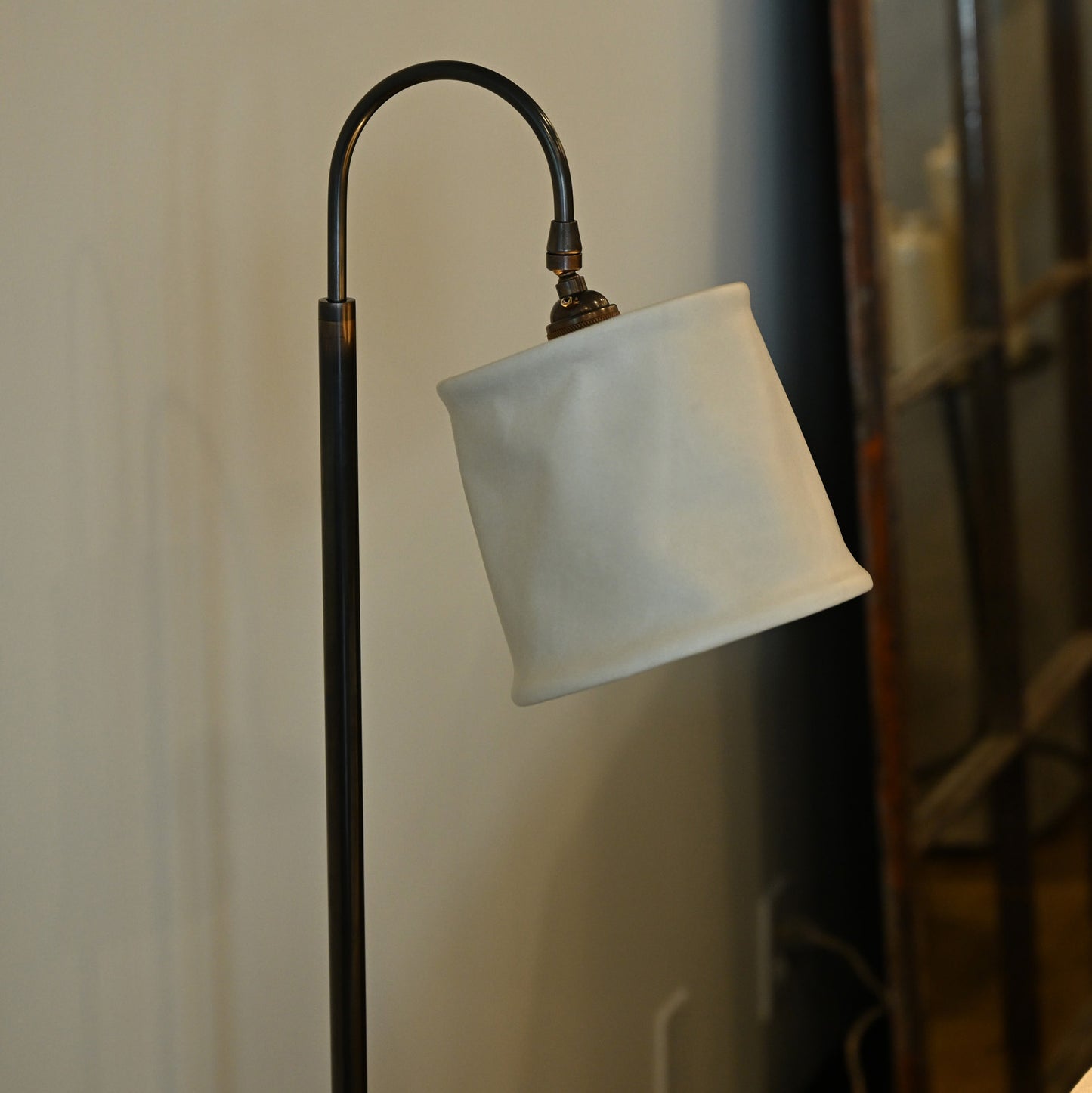 A sleek black metal floor lamp with curved neck and soft white fabric shade in brass and leather style