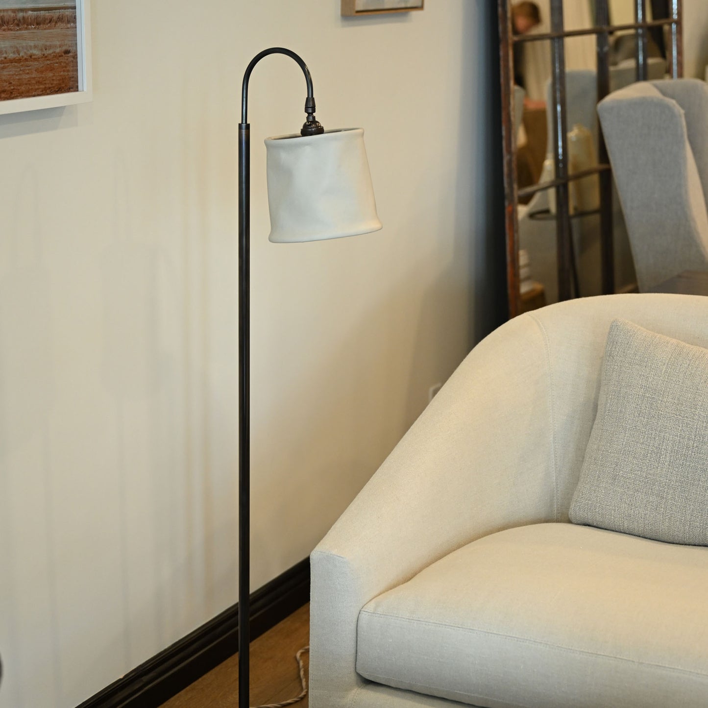 Black metal floor lamp with curved neck and white fabric shade in brass and leather floor lamp design