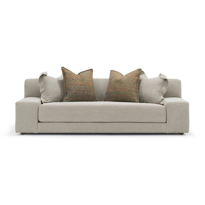 Beige upholstered custom order Esme sofa with two textured brown throw pillows and matching light gray accent cushions