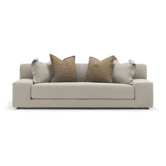 Beige upholstered custom order Esme sofa with two textured brown throw pillows and matching light gray accent cushions