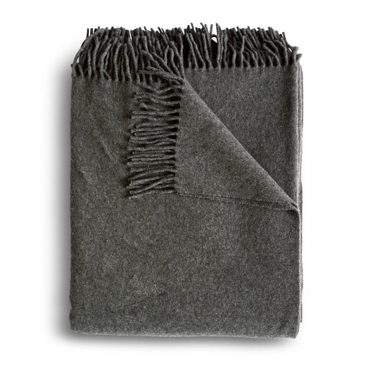 A soft dark gray cashmere throw blanket with textured surface and fringed edges in granite color
