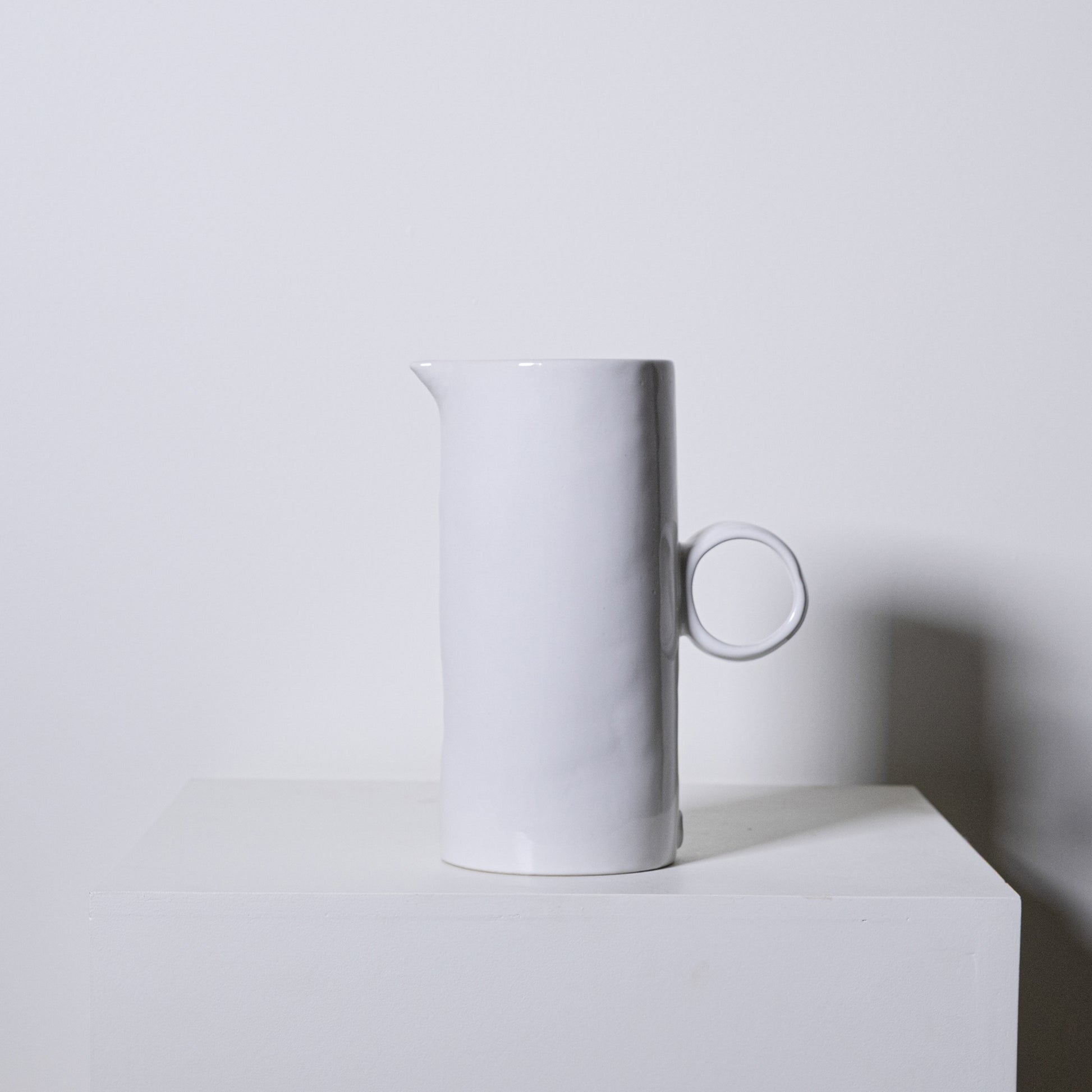 White ceramic fir pitcher no 923 with minimalist cylindrical body and circular handle for serving liquids