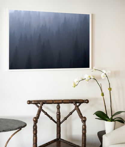 A framed photographic print titled ghost of day break featuring a misty forest in deep blues and grays in a white frame