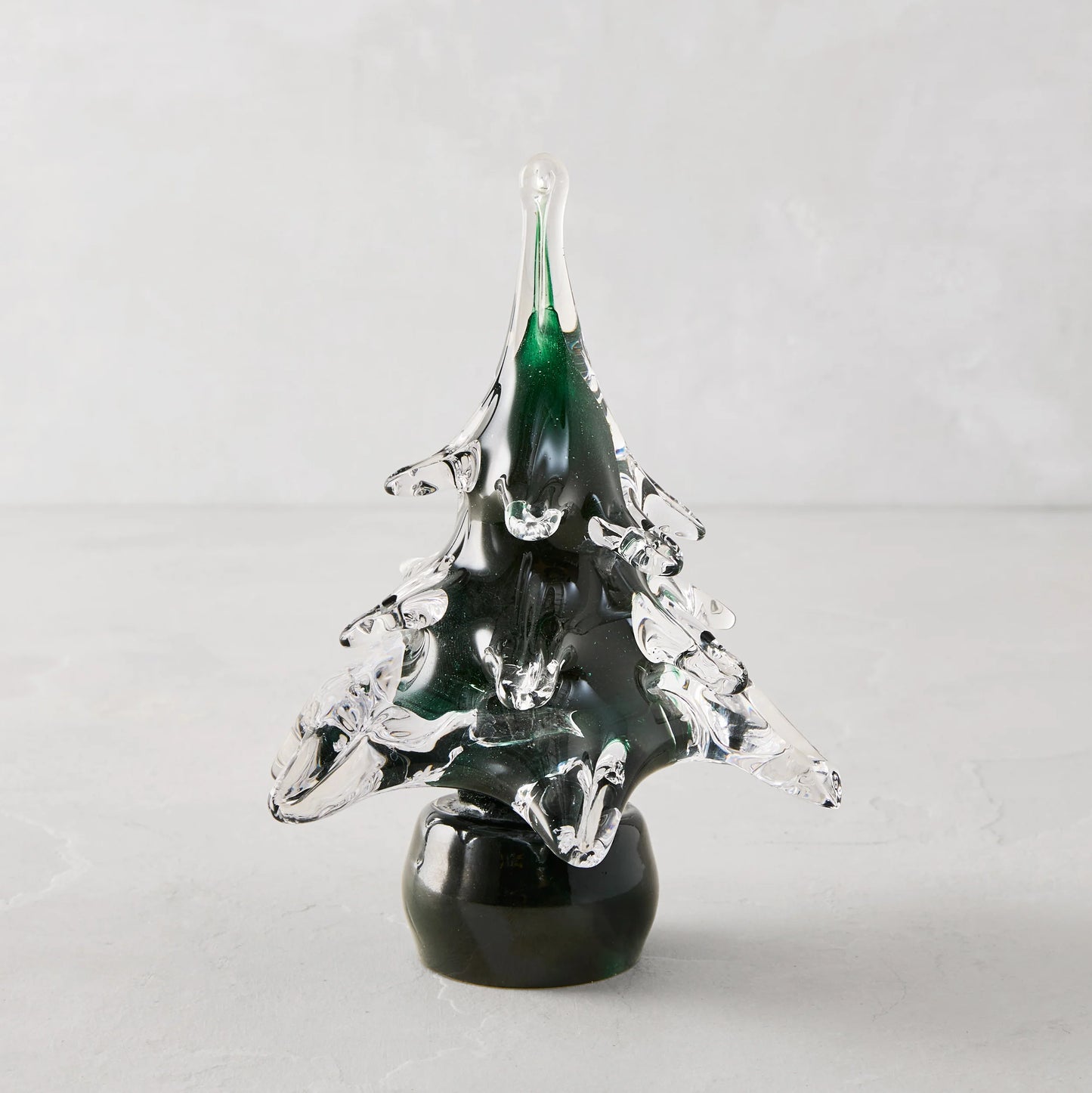 Green glass pine tree ornament made of translucent green and clear glass with a glossy black base for christmas decor