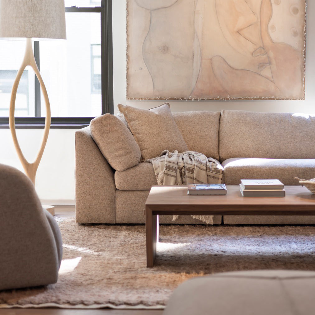 Beige textured fabric sectional sofa with matching throw pillows and woven blanket paired with custom order menorca coffee table