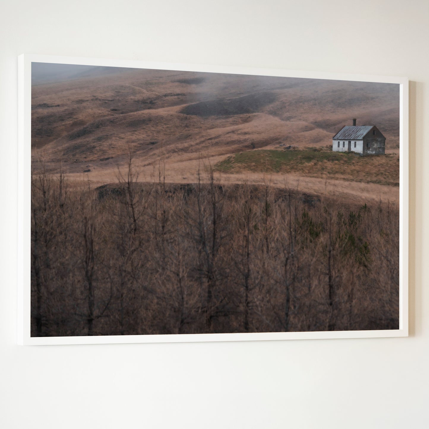 White-framed photograph titled House of Silence showing a solitary weathered house with dark roof in a barren landscape