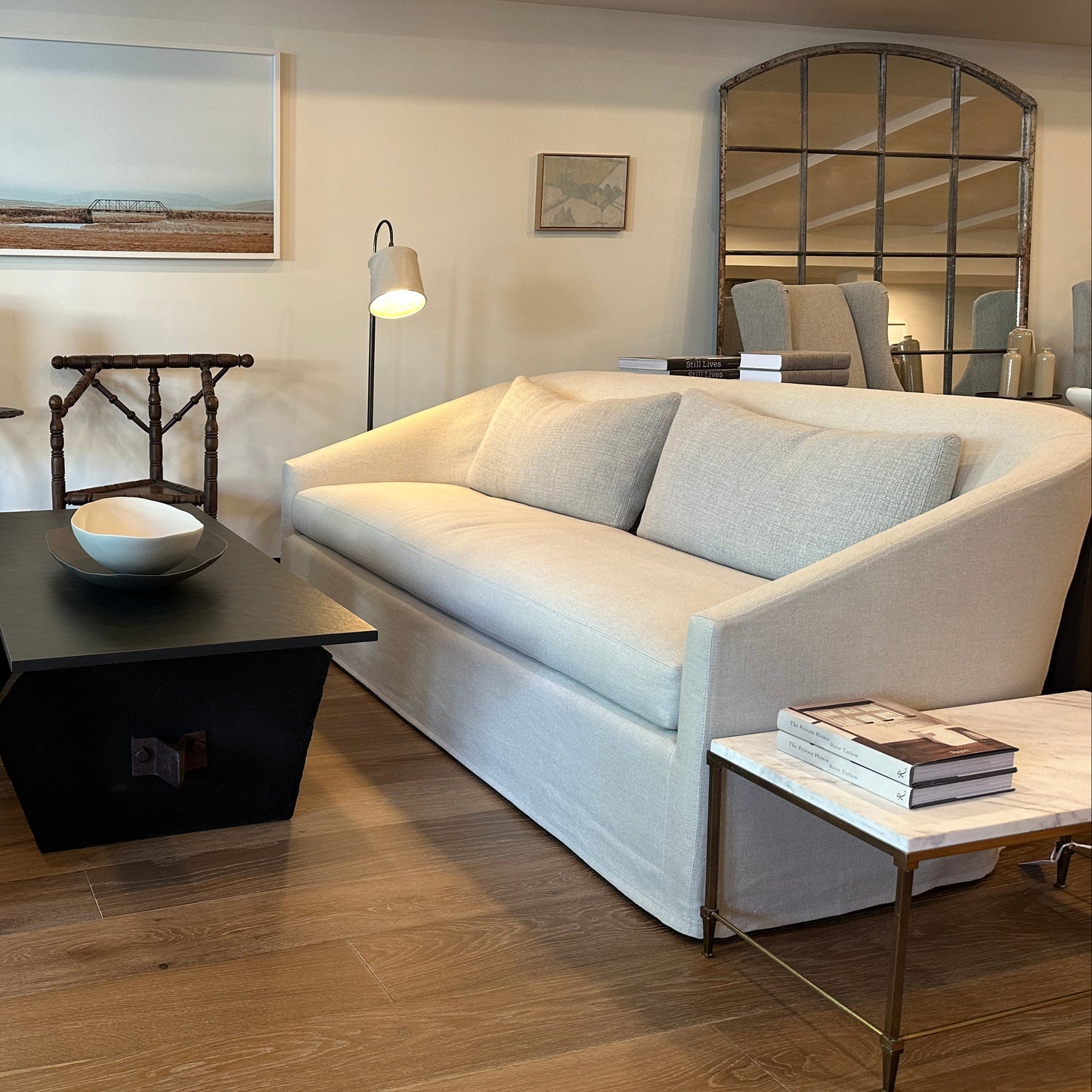 Cream-colored upholstered sofa with a modern, curved design and matching light gray throw pillows.