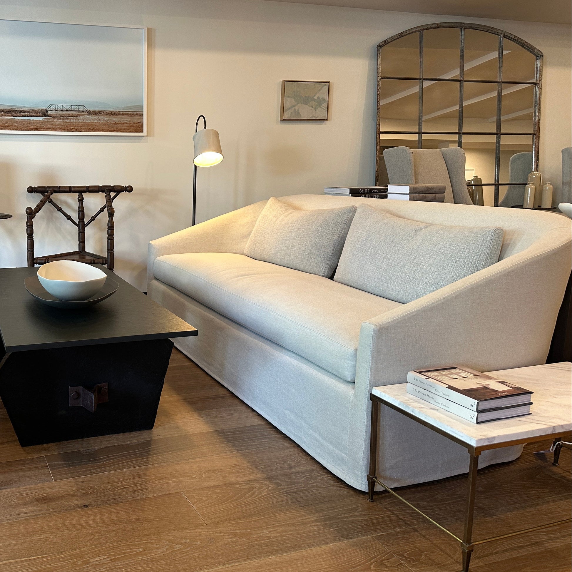 Cream-colored upholstered sofa with a modern, curved design and matching light gray throw pillows.