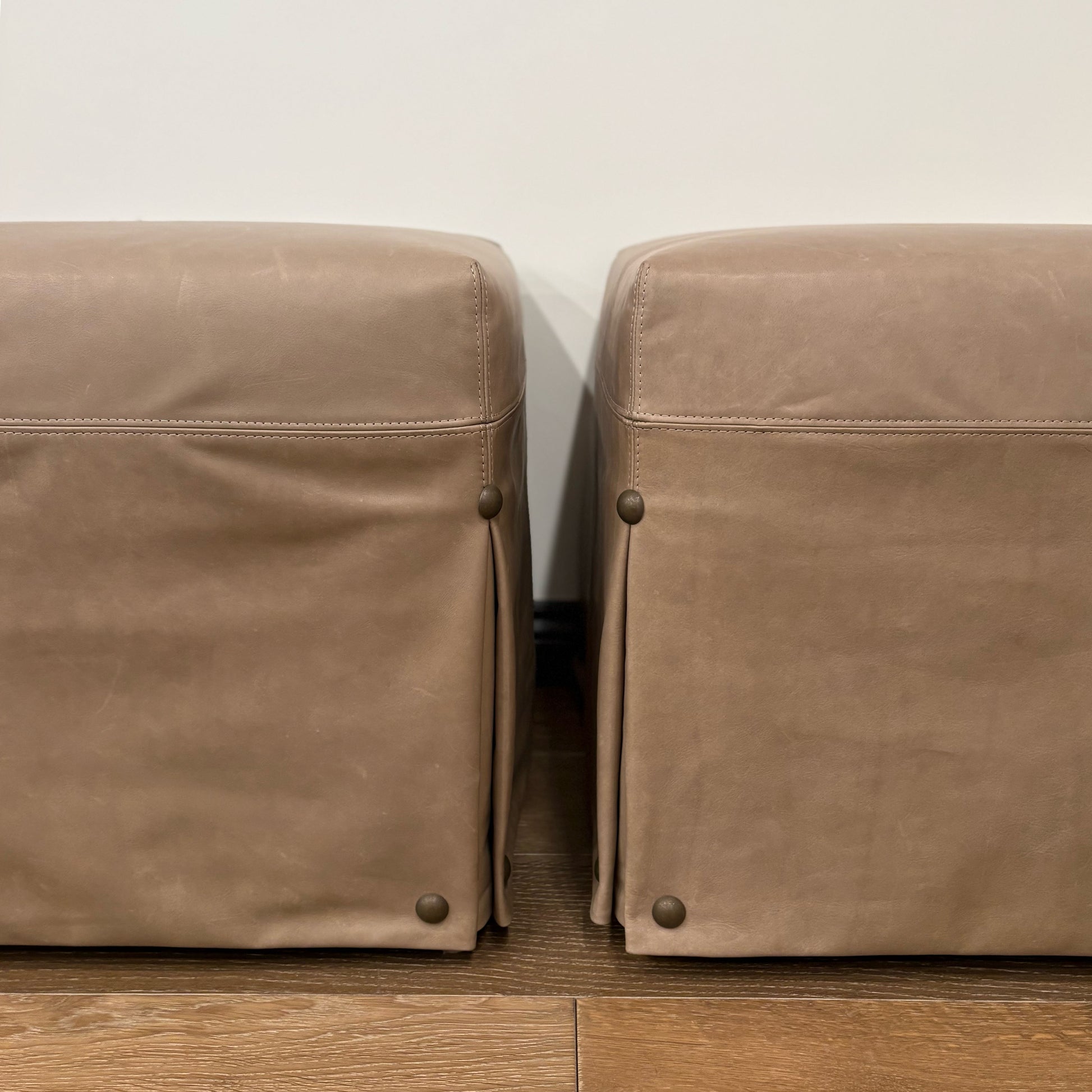 Kim leather slipcovered ottoman in tan with subtle stitching and brass-toned nailhead detail on corners floor model