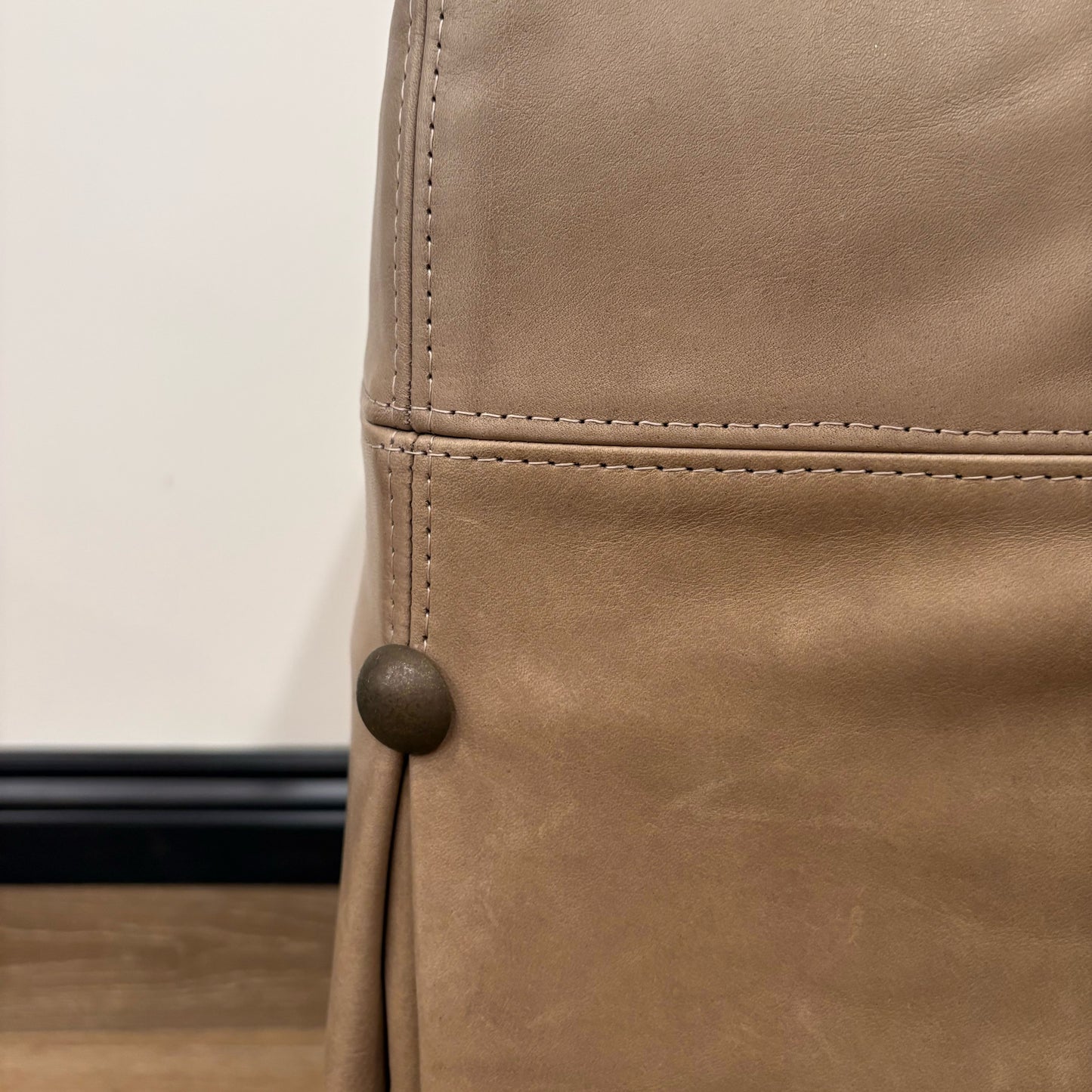 Tan leather skirt with subtle texture and dark brown button shown with kim leather slipcovered ottoman floor model