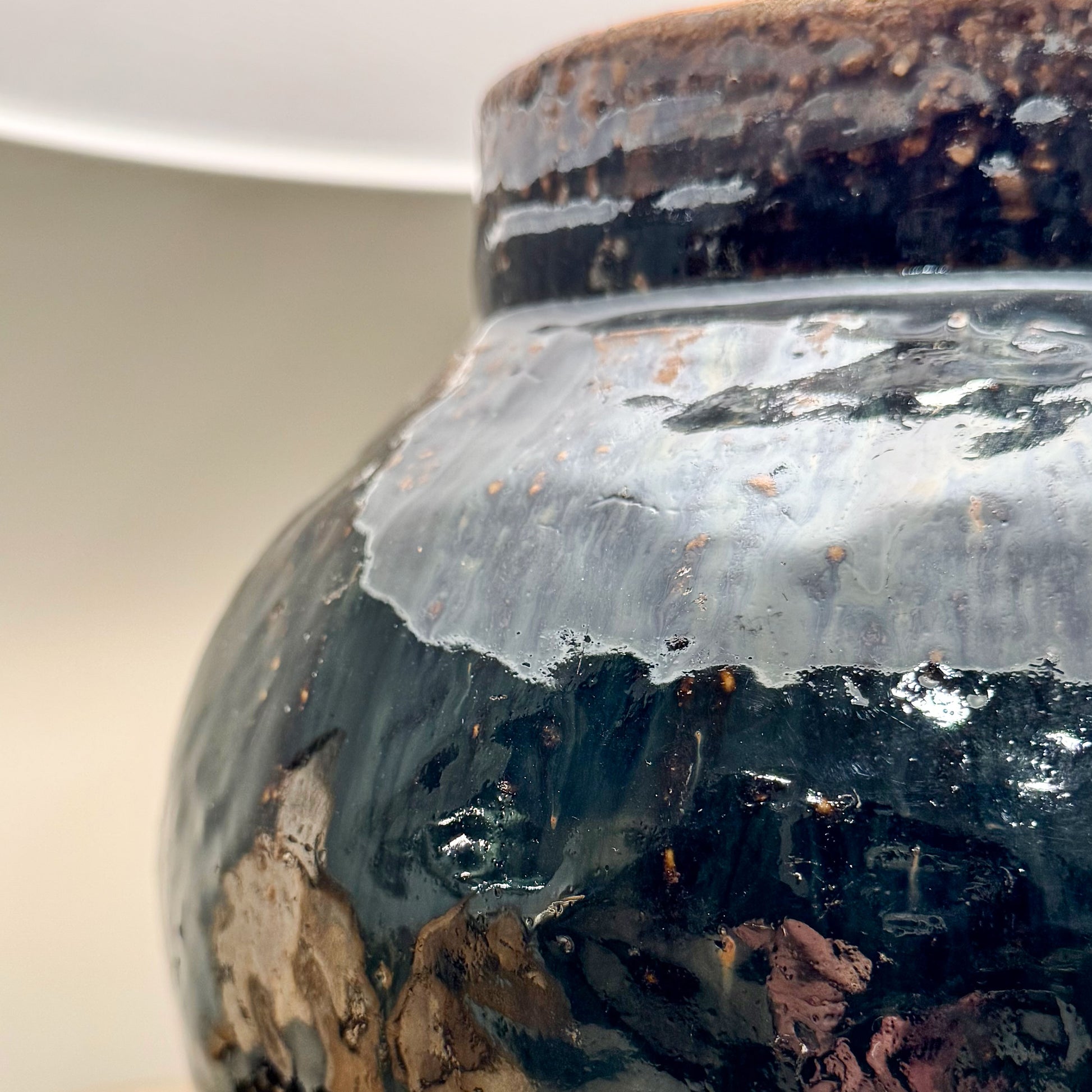 A glossy dark ceramic mid century Shanxi glazed pot table lamp with textured speckled rim and swirling glaze patterns