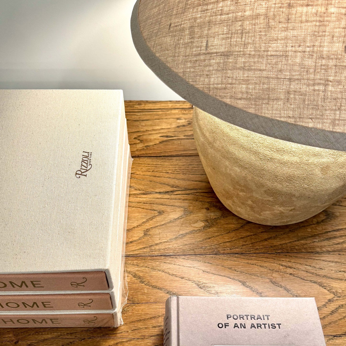 Beige linen-covered book with rizzoli embossed in gold lettering shown with mid century shanxi clay pot table lamp