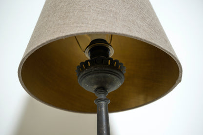 Close-up of a lamp with a beige shade and black metal base.