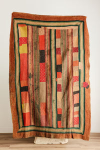 Dahlia quilt featuring a rustic patchwork with vertical stripes in earthy tones and a frayed border