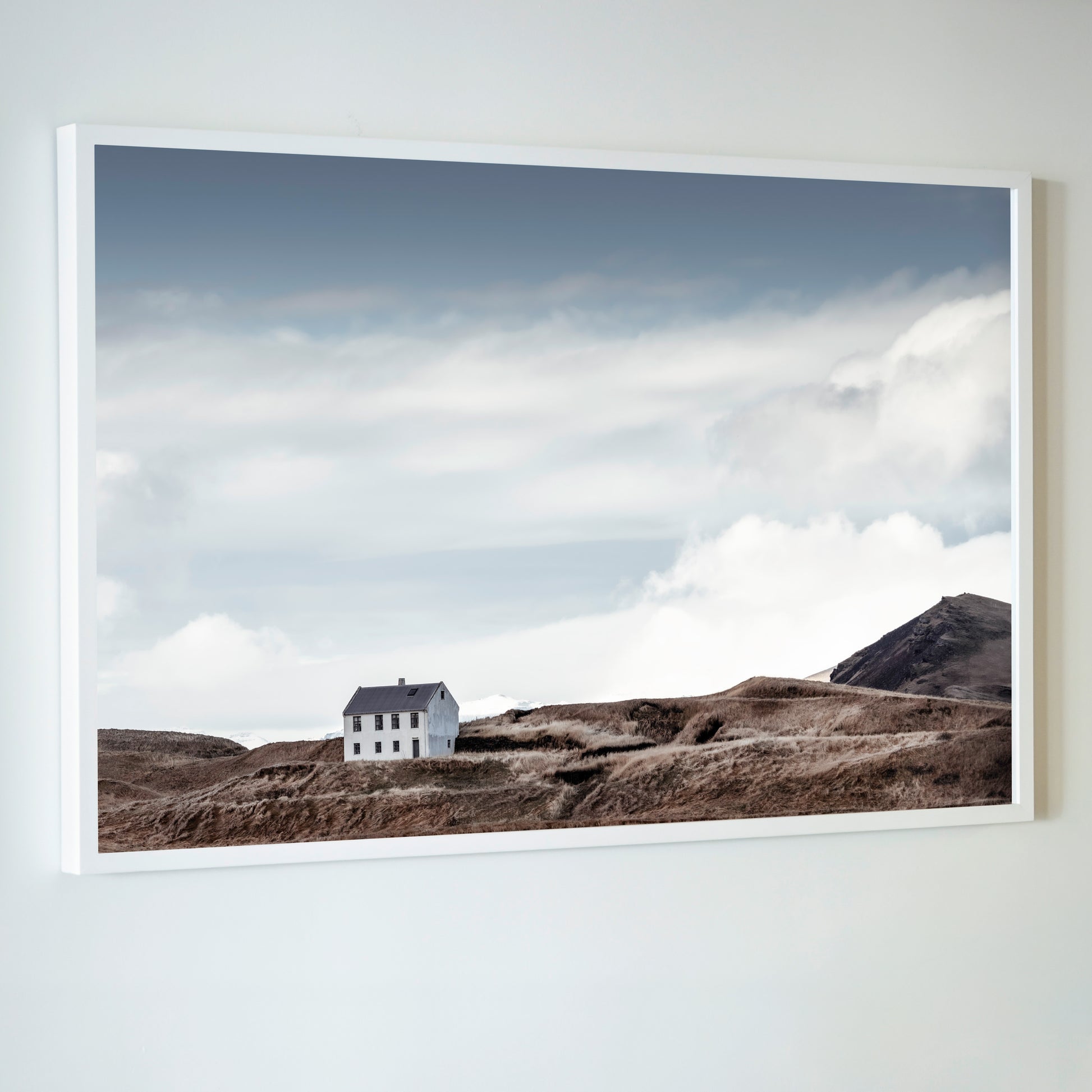 Framed photograph of a house on a hillside with a cloudy sky