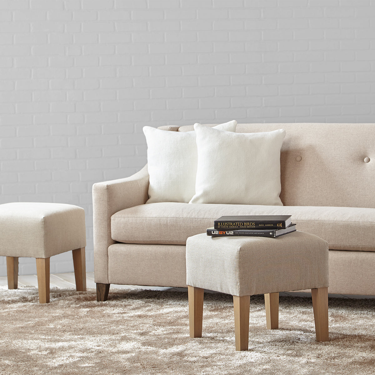 Beige upholstered custom order Palisades sofa with tufted back and matching ottomans in a living room setting