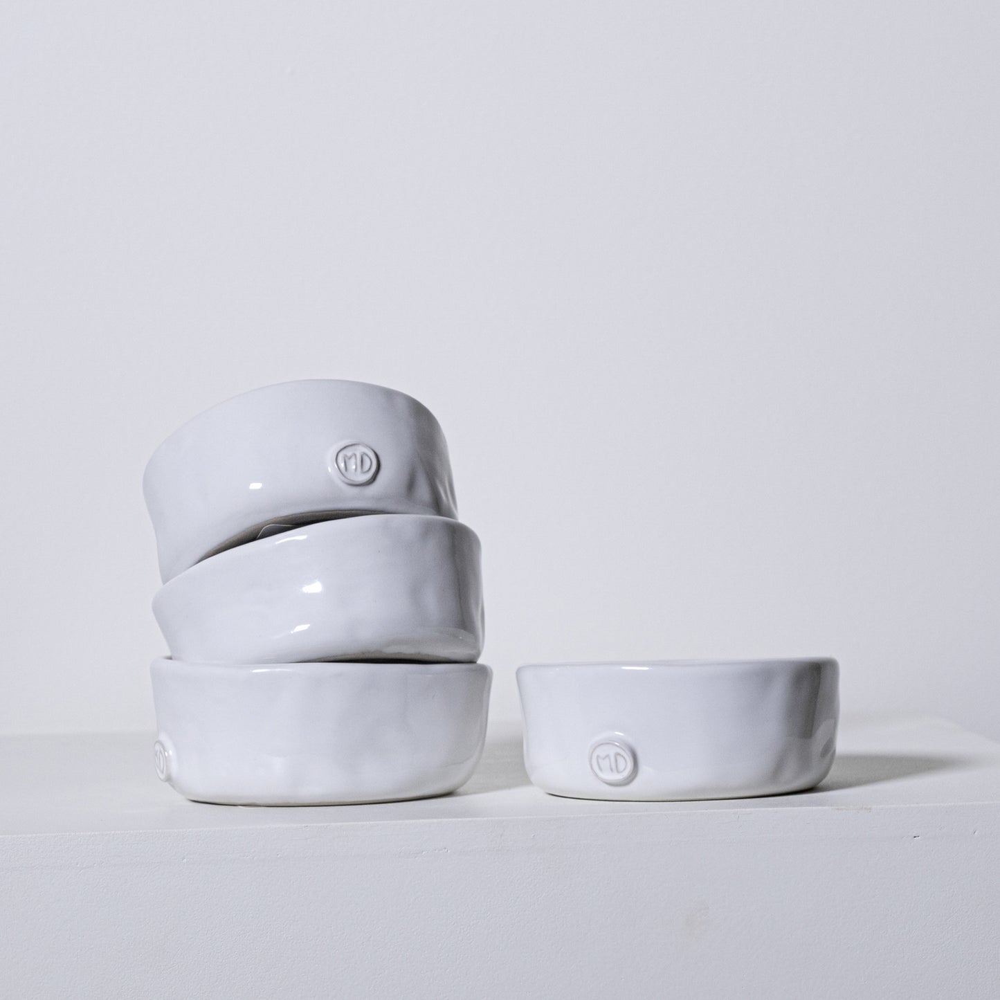 Stack of four minimalist white ceramic linden bowls no 803 with subtle matte finish and embossed logo