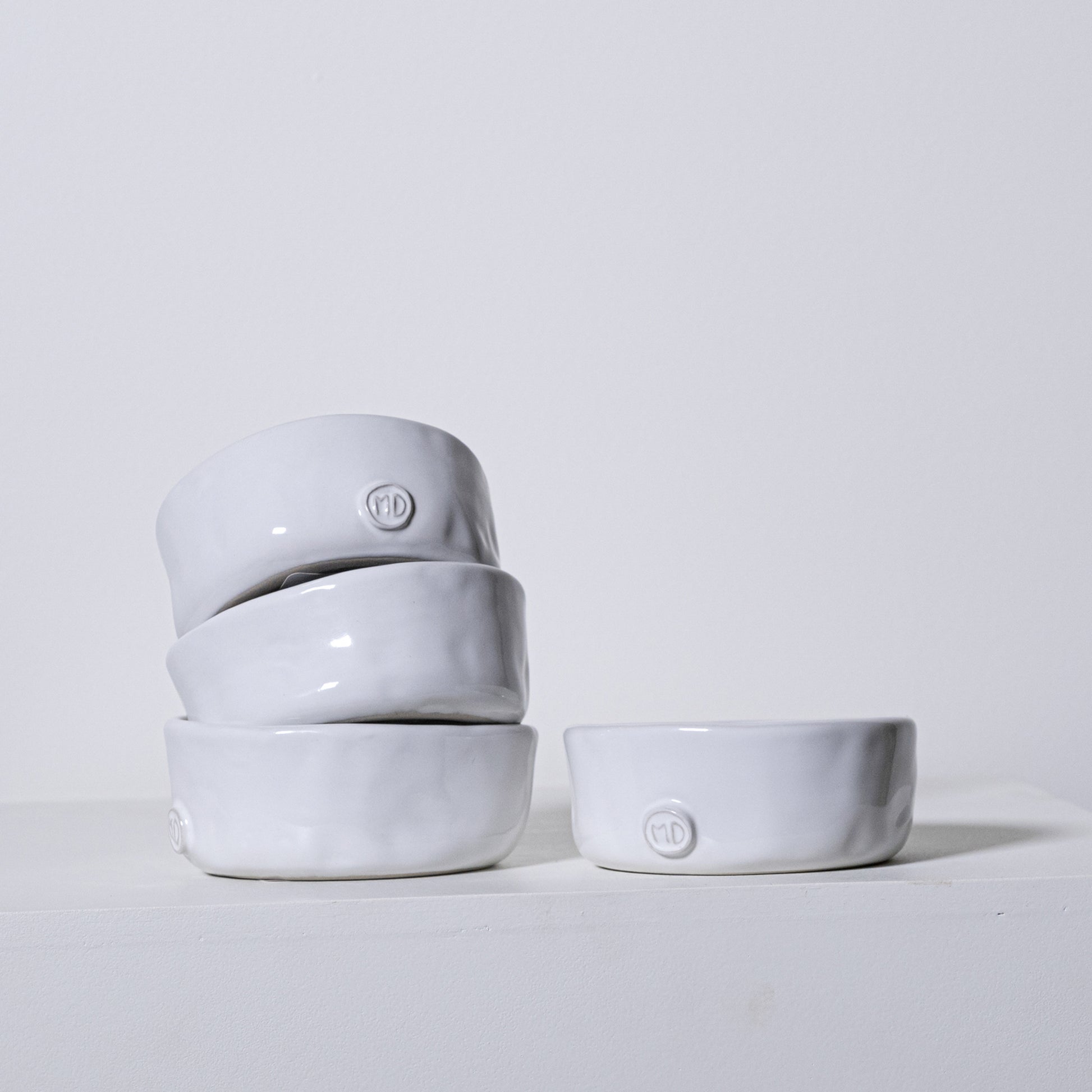 Stack of four minimalist white ceramic linden bowls no 803 with subtle matte finish and embossed logo