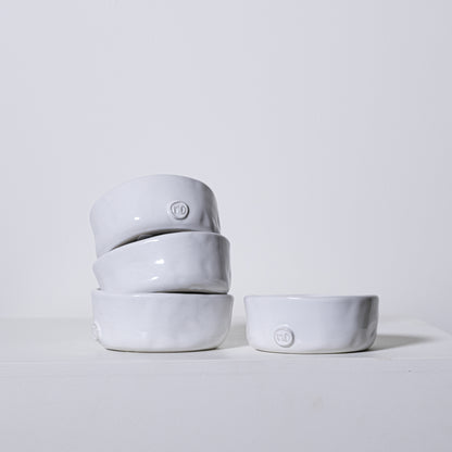 Stack of four matte white ceramic linden bowls with textured rims and small circular logos on each bowl