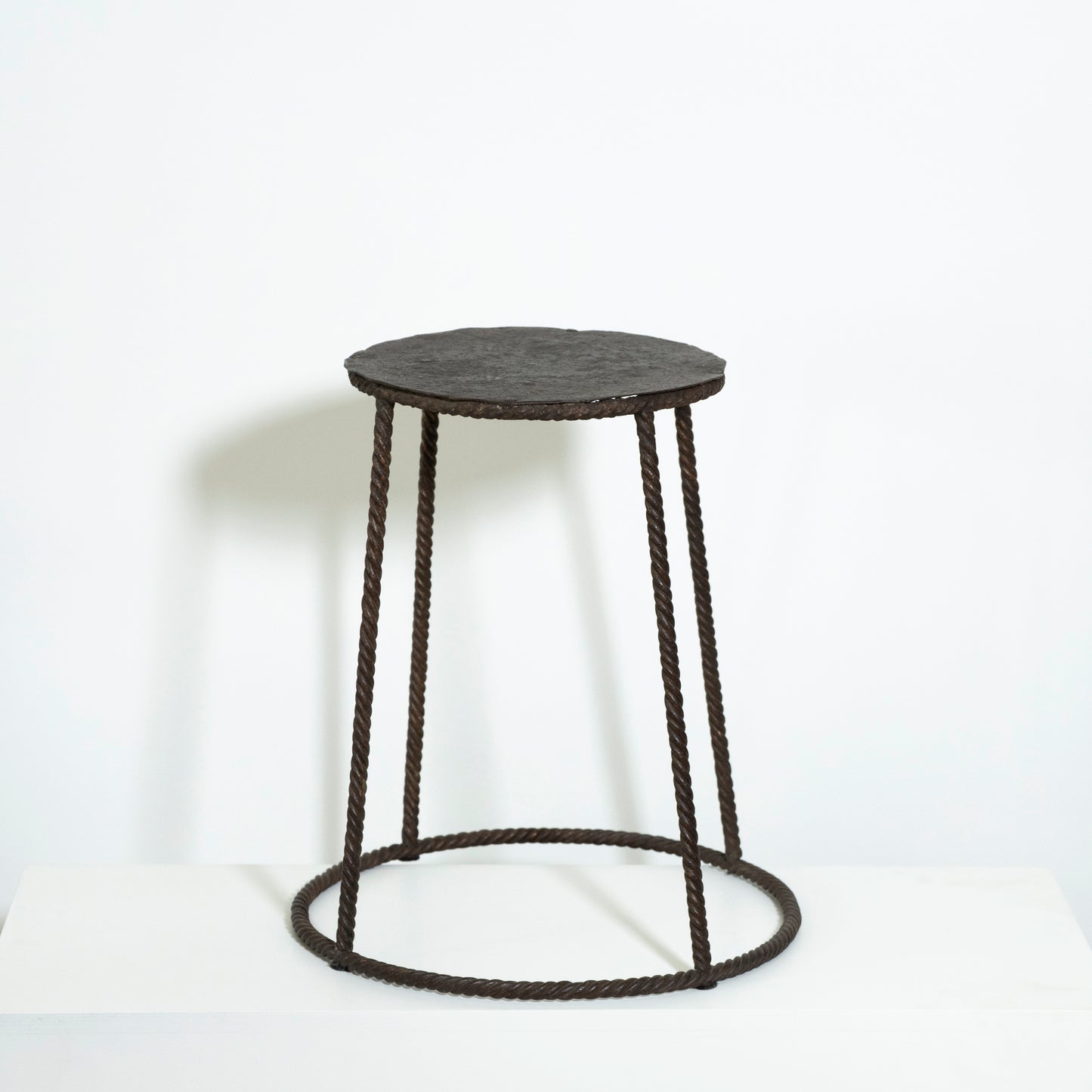Round stool with black woven design on a white background