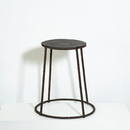Round stool with black woven design on a white background