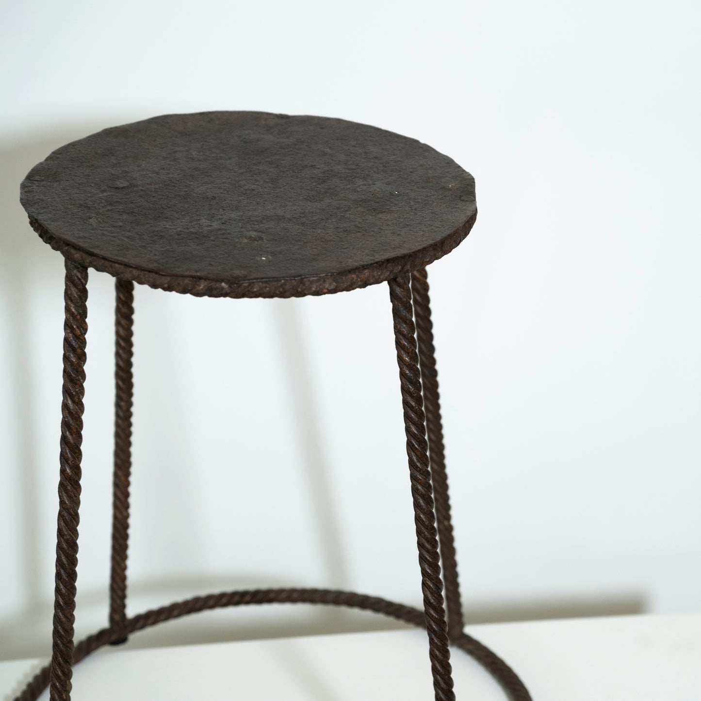 Round black stool with woven design on a white background