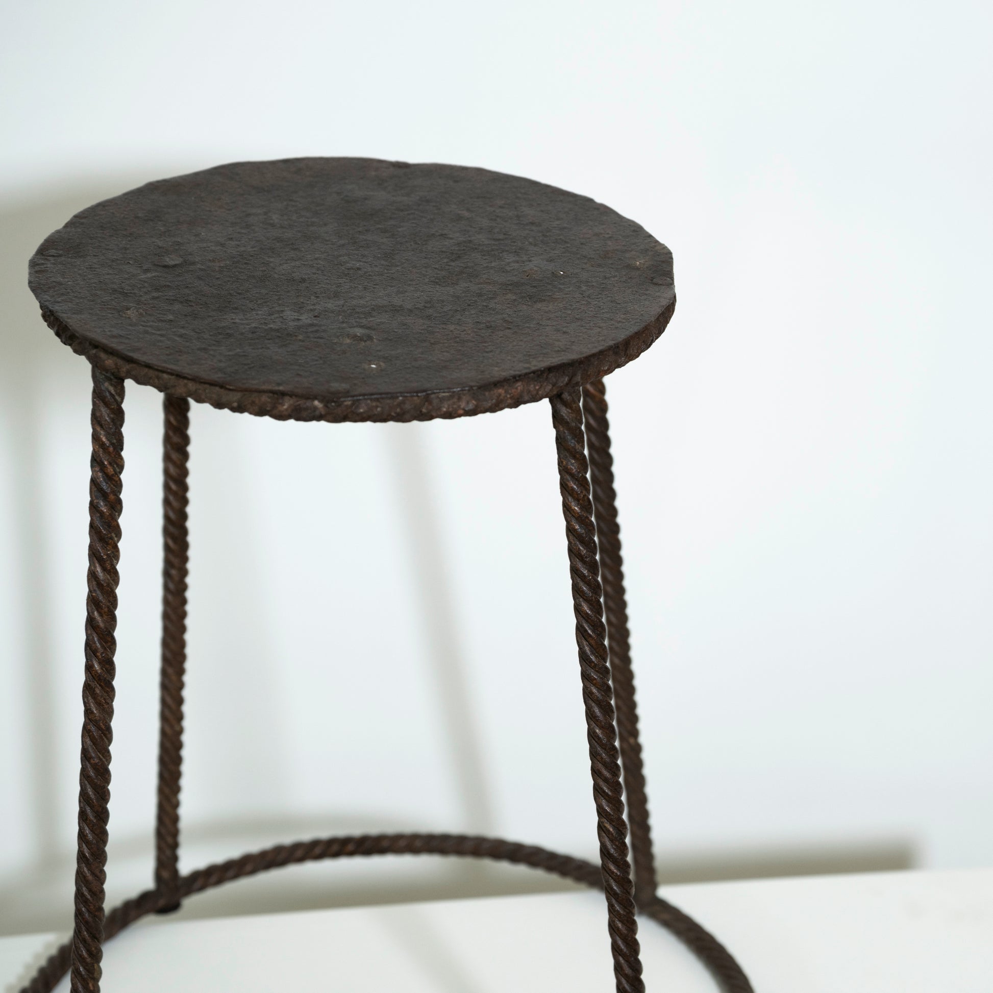 Round black stool with woven design on a white background