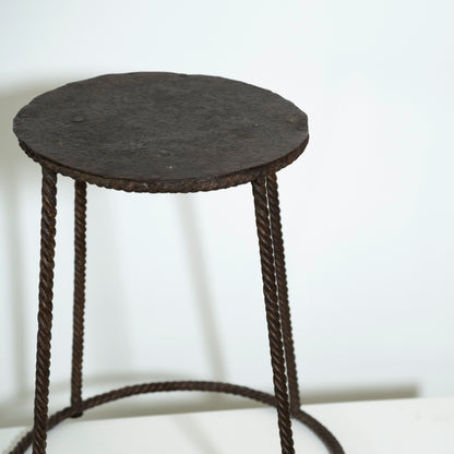 Round black stool with woven design on a white background