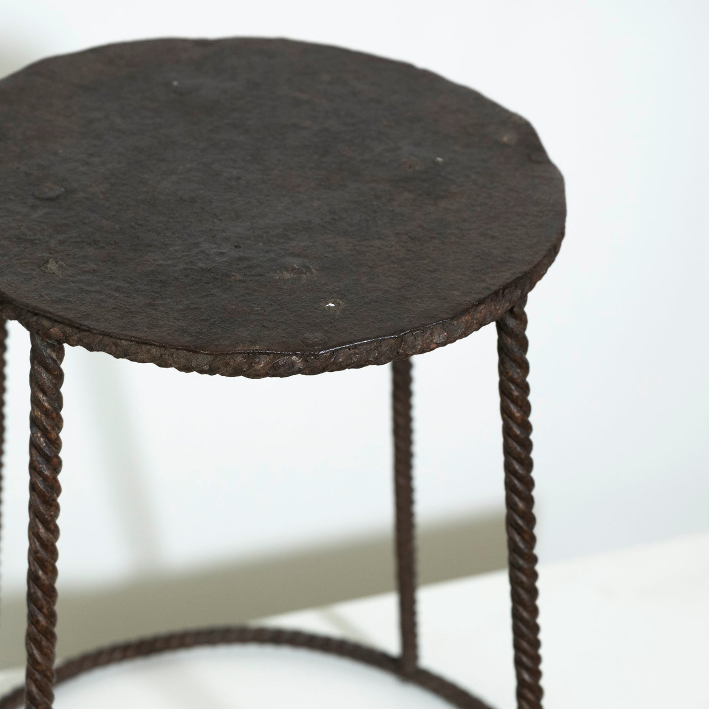 Small round table with a dark surface and rope-like legs on a white background