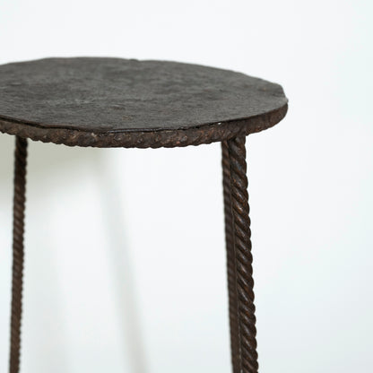Round side table with textured surface and rope-like legs on a white background