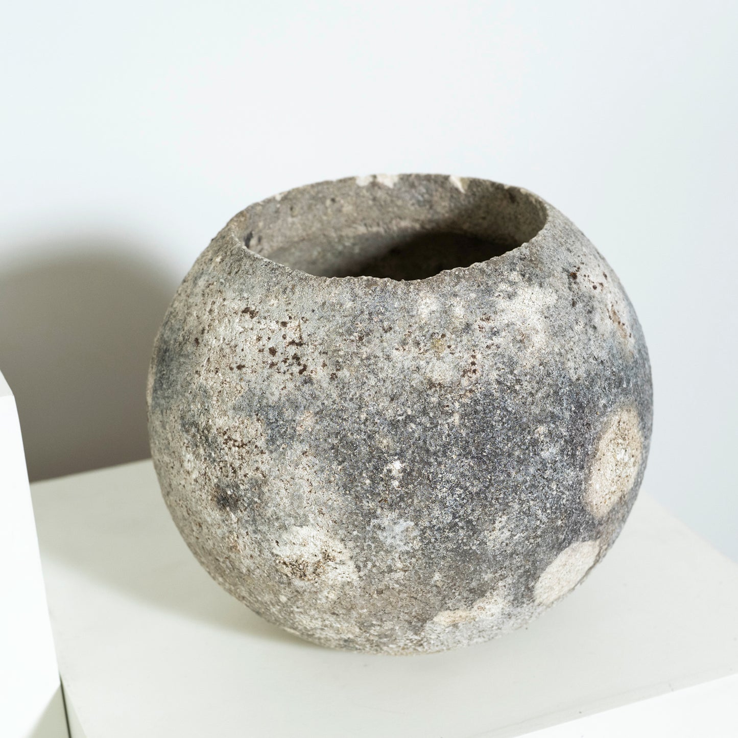 Textured stone bowl on a white surface with a neutral background
