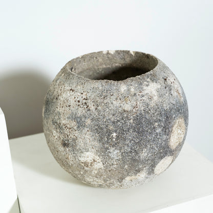 Textured stone bowl on a white surface with a neutral background