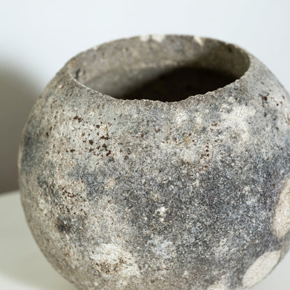 Close-up of a textured stone-like vase on a white background