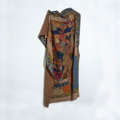 A quilt with an intricate, multicolored patchwork design featuring blue, gold, red, and beige tones