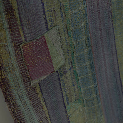 Close-up of a textured quilt with vertical striped panels in muted olive green.