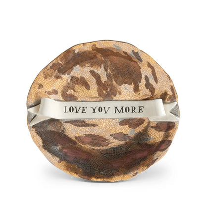 A round crackled ceramic ruan hoffman plate with rustic brown and gold glaze and white ribbon band inscribed love you more