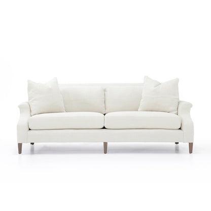 Cream-colored custom order Rafael sofa with rolled arms upholstered in fabric and wooden legs