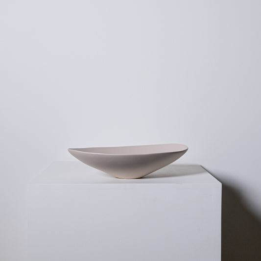 A sleek matte-finished ceramic bowl with modern asymmetrical design in greige color called Baccello Small