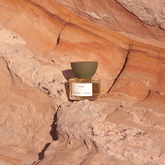 A minimalist glass perfume bottle with matte olive-green cap and white label for Maison dEtto fragrance Canaan