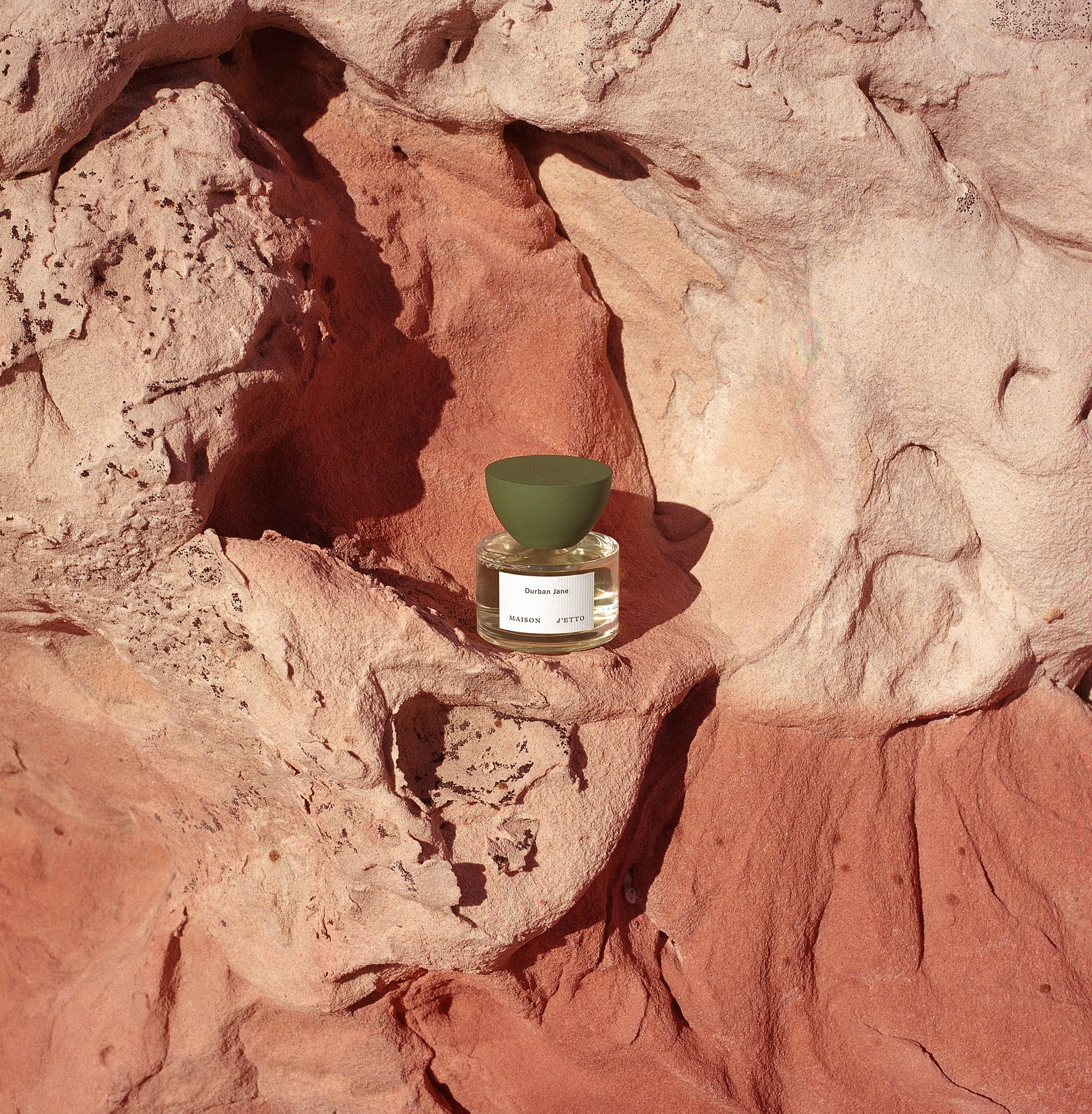 A minimalist maison dette fragrance durban jane perfume bottle with clear glass body olive green cap and white label