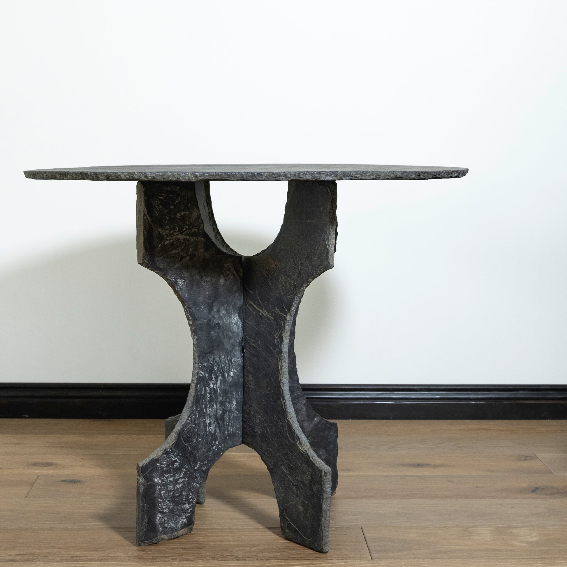 Black marble dining table with unique base design on a wooden floor.