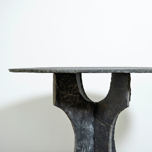 Black metal table with a unique base design on a white background