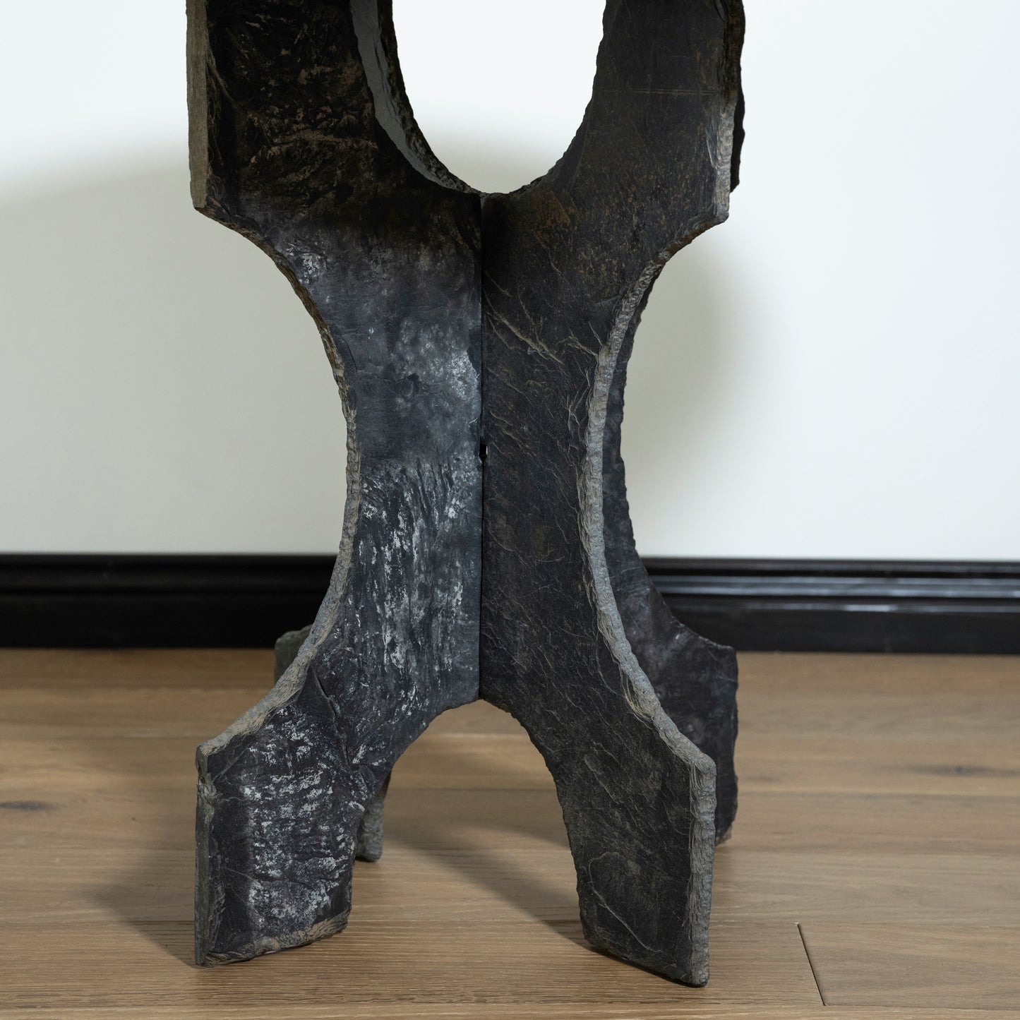Decorative stone sculpture on a wooden floor with a white wall background