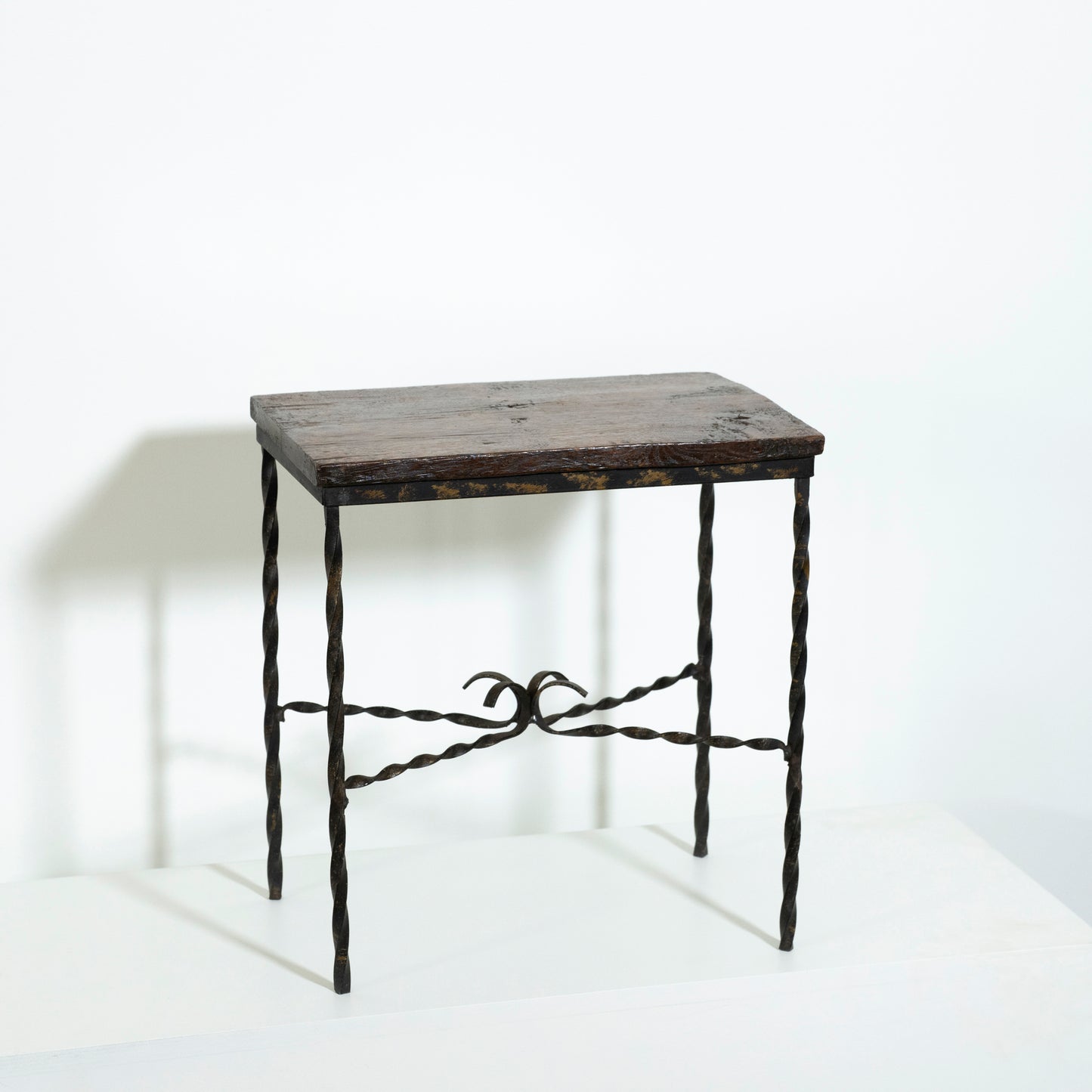 Small wooden table with wrought iron legs on a white background
